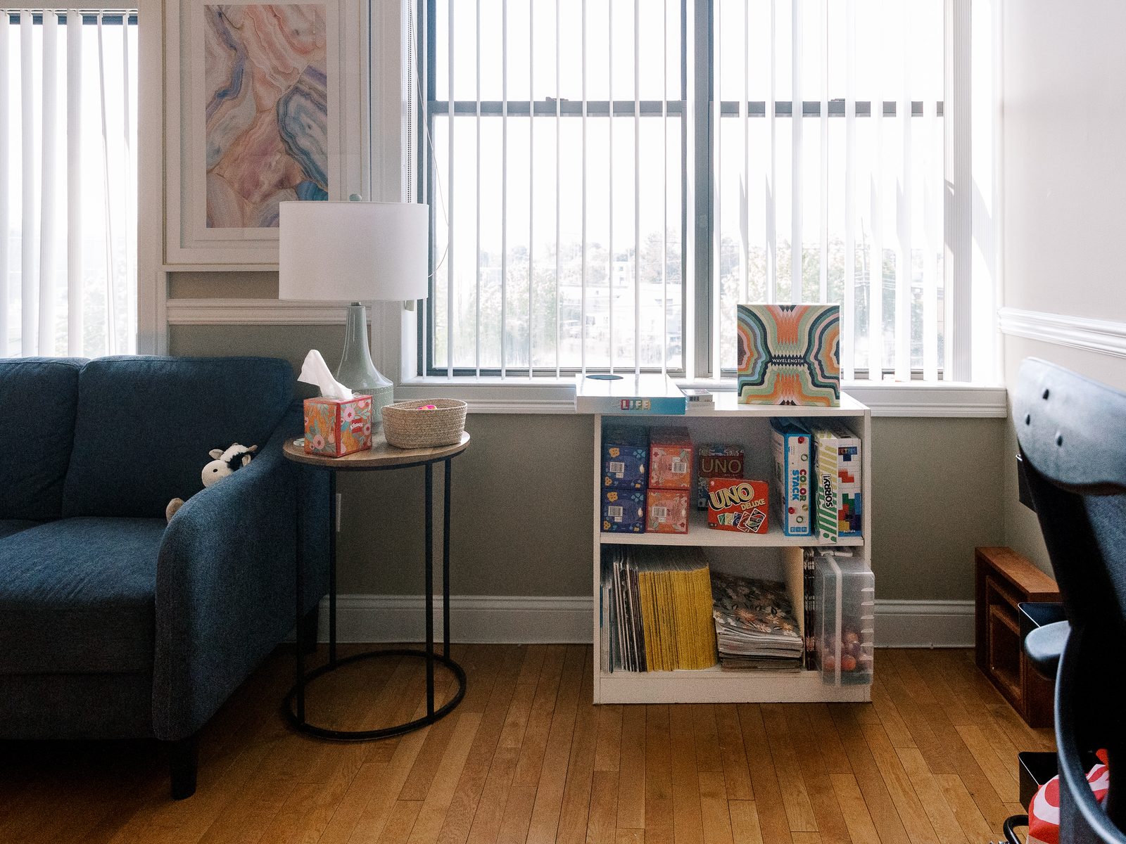 A bright room at the CMHS Plains Road office in Milford, with a blue couch and a shelf of games
