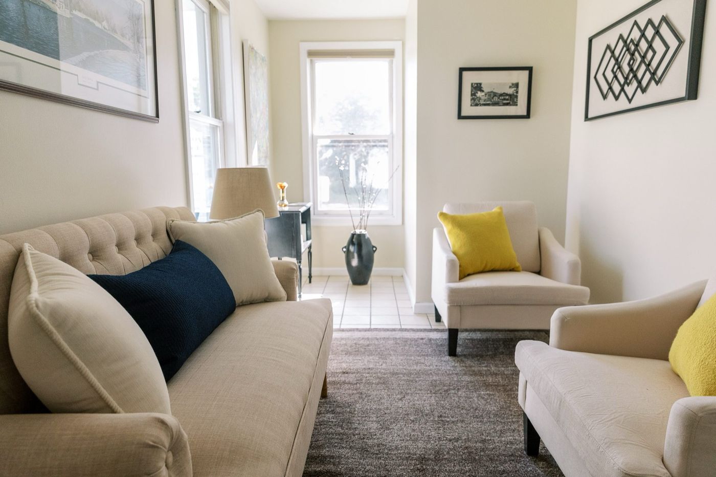 A calm therapy office at CMHS in Milford with a linen sofa, navy accent pillow, and warm natural light